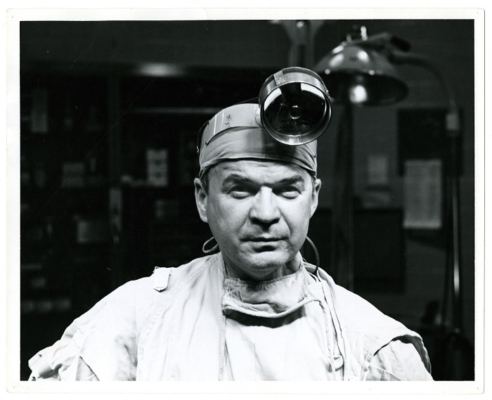 Photo of Dr. C. Walton Lellehei, wearing surgical scrubs and a head lamp.