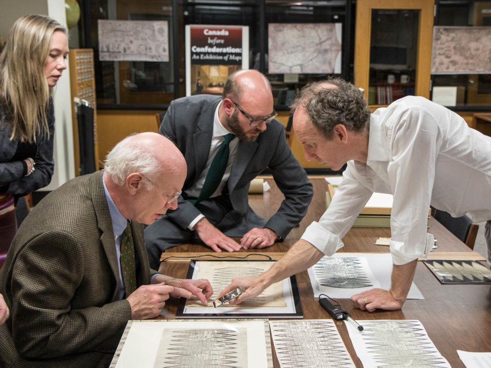 Representatives from Christie's examine the Bell Library's print of the Waldseemüller map