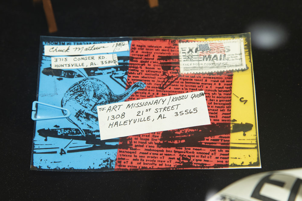 Mail art from the Stamped and Posted exhibit features a colorful background with text and line art.