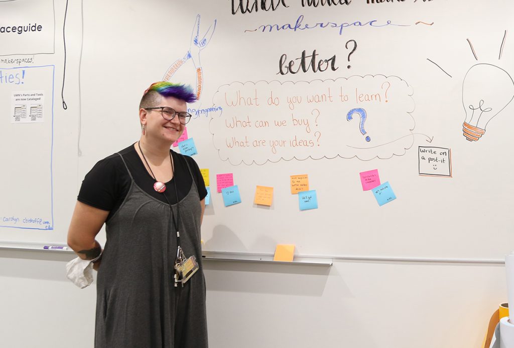 Librarian Carolyn Bishoff smiles while standing near the whiteboard in the Makerspace