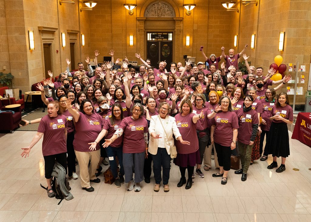 Group portrait of all the attendees wearing identical maroon T-shirts at the Walter Library at 100: An Afternoon Tea celebration