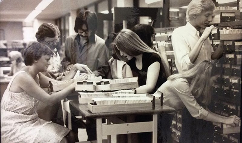Black and white photo of librarians looking at card catalogs.