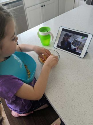 A young child watches virtual StoryTime on a tablet.