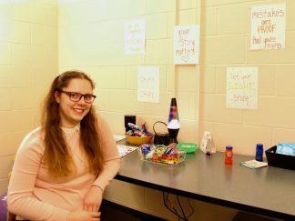 Student sitting in front of desk with fidget toys and handwritten signs.