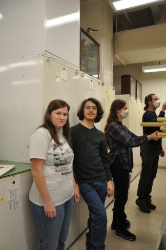 Four people standing in the bird specimen repository.