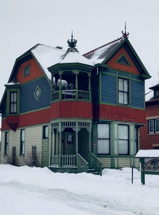 Victorian-era home, multi-colored, with roof spires; a snowy day.