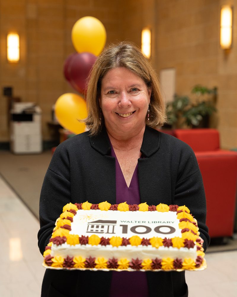 Dean Lisa German holds a cake that reads, "Walter Library 100"