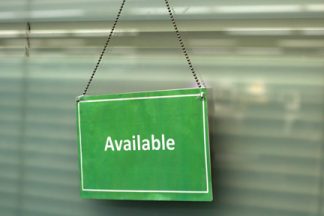 Green sign with "available" printed on it hanging from the door of the 1:Button Studio.