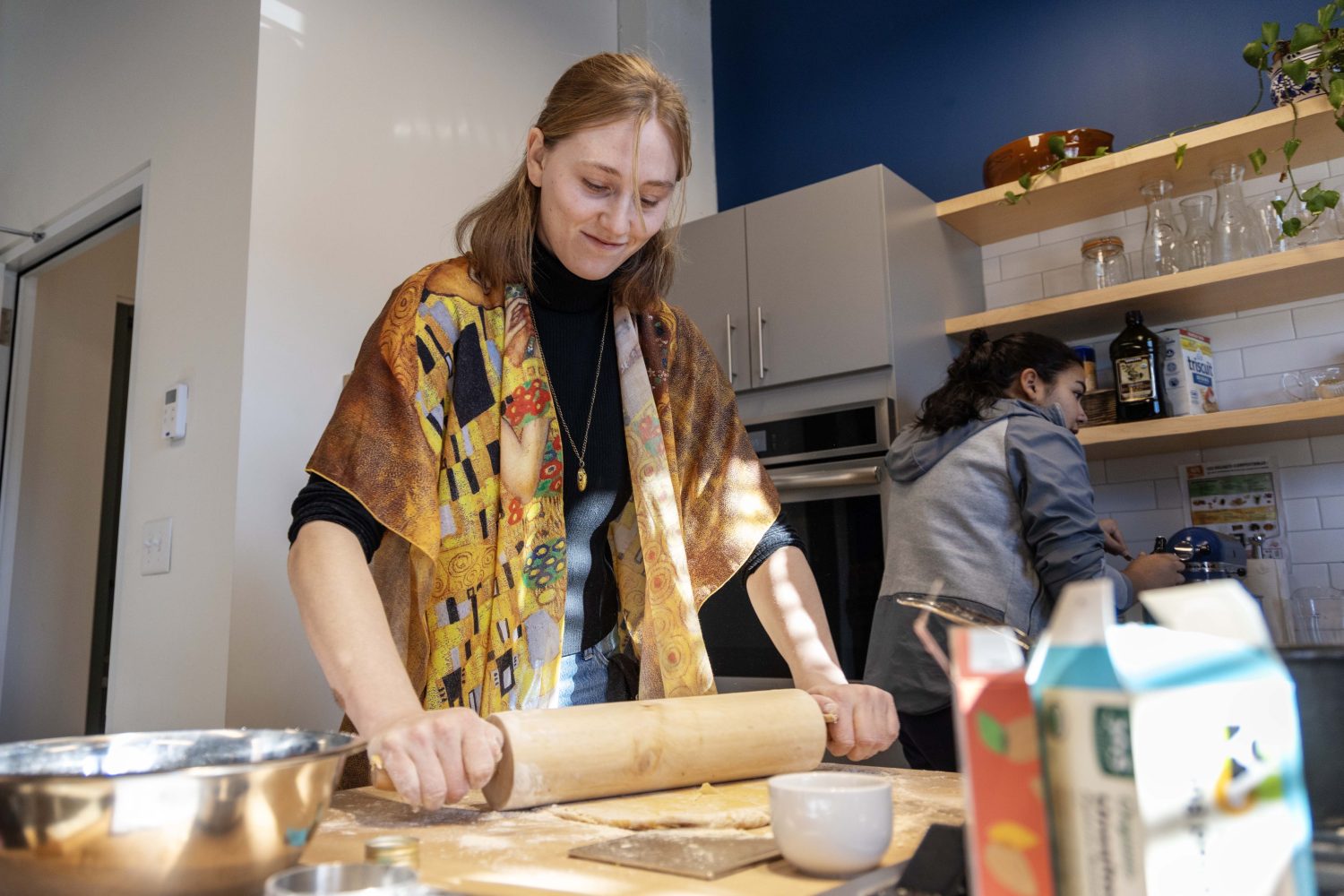 A student uses a rolling pin to roll out the beignet dough