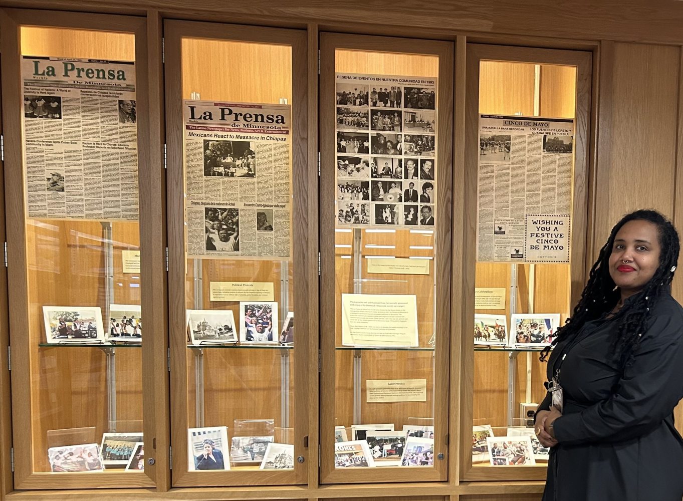 Ayantu Tibeso stands in front of the display case outside IHRCA, sharing some of the "La Prensa de Minnesota" materials.