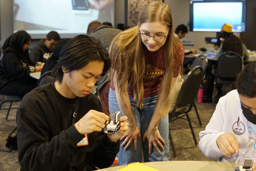 A Library student staffer helps a teen with wiring an LED matrix.
