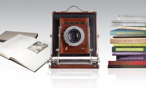 an old box camera with stacks of books on either side