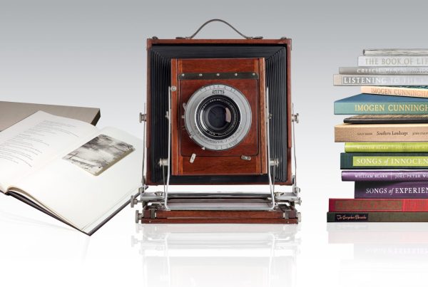 an old box camera with stacks of books on either side