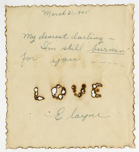 Letter with burn marks around the edges, and the word LOVE burned into the paper.