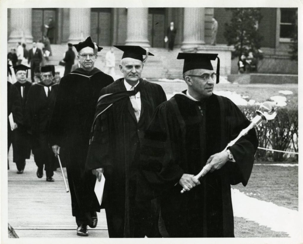 Professor Alfred O. Nier leads University of Minnesota President O. Meredith Wilson in his inauguration procession, February 23, 1961. Nier is carrying the university mace which made its debut during Wilson's inauguration ceremony. University of Minnesota Archives Photograph Collection, https://umedia.lib.umn.edu/item/p16022coll175:15100.