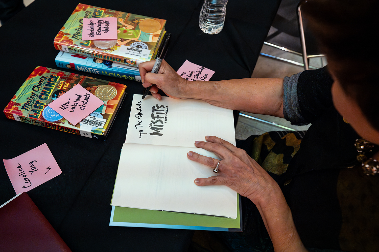 Shot from above of author Lisa Yee signing a copy of her book The Misfits