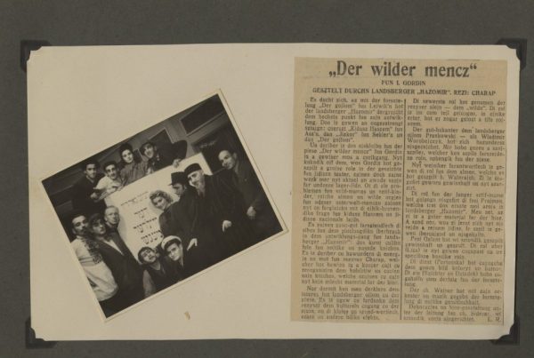 Scrapbook page with image of the entire “Hazomir” theater troupe posing in front of a sign for their production of “Der Wilder Mencz” (The Unusual Person), with accompanying newspaper article about the production in Yiddish at right. Eugenia Lewin/Jeanette Frank pictured middle-row center. Source: Jeanette and Kenneth Frank Papers, Upper Midwest Jewish Archives.