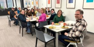 Several people sitting at tables and smiling at the camera.