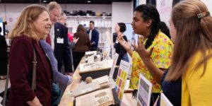 Four individuals looking at and talking with each other, with a table of rare books open between them.