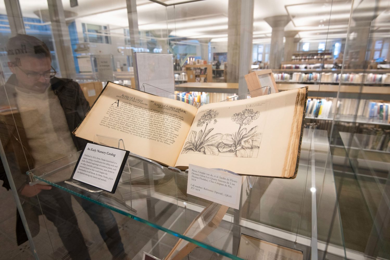 Display case at the Flora and Fauna Illustrata exhibit at the Minneapolis Central Library featuring an old book held open with sketches of flowers and text in a european language