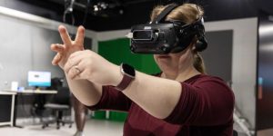 Student wearing a virtual reality headset and manipulating the virtual environment with her hands.