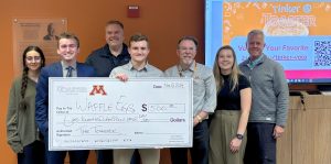 group of individuals one holding a giant sized check pose for a winners picture.