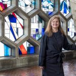 Jennifer Yoos, environmental portrait with stained glass hexagonal windows in the background