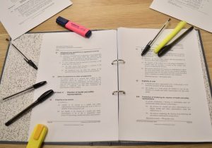 Binder with research articles and highlighters.