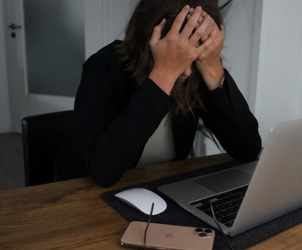person in front of computer holding head in frustration