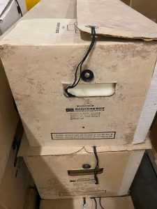 Two boxes containing archival records stacked on top of each other showing pest damage and fading