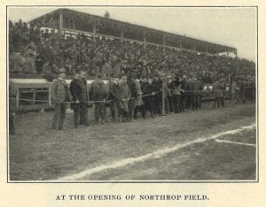 Image printed on a page of the Ariel student newspaper depicting spectators standing on the sidelines of a field with additional spectators seated behind them in the bleachers. The image includes the caption, "At the Opening of Northrop Field."