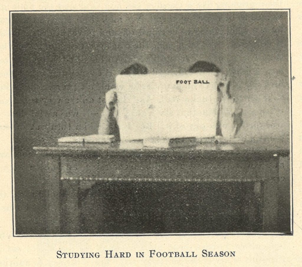 Image printed in an issue of the Ariel student newspaper depicting two students seated at a desk holding an issue of the publication FOOT BALL in front of their faces. The image includes the caption, "Studying Hard in Football Season."